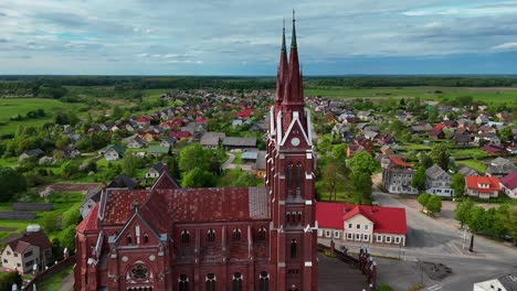 A-gothic-church-with-a-quaint-village-backdrop-in-lithuania,-aerial-view
