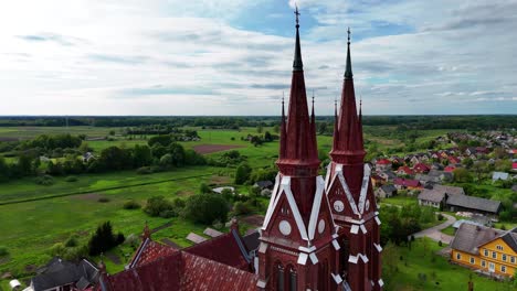 Sweeping-aerial-view-of-Švėkšna-Church-towers-amidst-lush-green-countryside-in-Lithuania