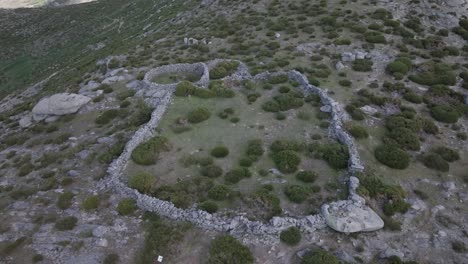 flight-in-retreat-and-ascent-with-a-drone-visualizing-a-closed-stone-enclosure-with-2-attached-structures-used-for-livestock-and-previously-for-bullfighting-celebration-events-until-the-17th-century