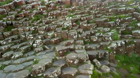 Aerial-pan-from-left-to-right-of-the-basalt-stones-at-Giant's-Causeway,-County-Antrim-in-Northern-Ireland-on-a-sunny-morning