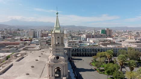 Erleben-Sie-Einen-Herrlichen-Panoramablick-Auf-Die-Türme-Der-Kathedrale-Von-Arequipa-In-Einer-Aufregenden-Schwenkbewegung-Von-Links-Nach-Rechts,-Mit-Dem-Imposanten,-Nebligen-Vulkan-Im-Hintergrund