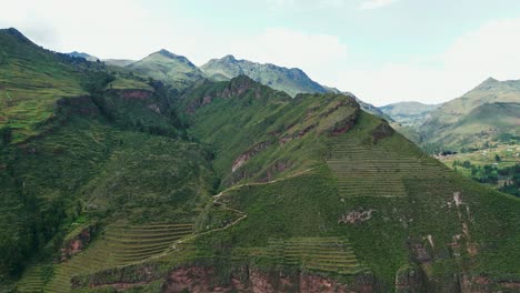 Witness-the-majesty-of-Pisac-Valley-from-the-air,-with-its-terraces,-ruins,-and-lush-greenery-under-the-midday-sun