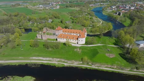 Aerial-establishing-view-of-Bauska-Medieval-Castle-and-ruins,-Musa-and-Memele-rivers-next-to-the-castle,-sunny-spring-day,-distant-orbiting-drone-shot