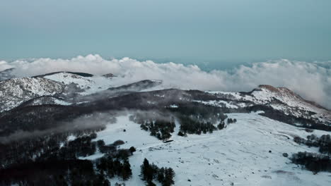 Snowy-mountain-landscape-with-clouds-drifting-over-peaks-and-forests