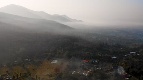Aerial-view-of-mist-covering-the-mountain-landscape-of-Pai,-Thailand