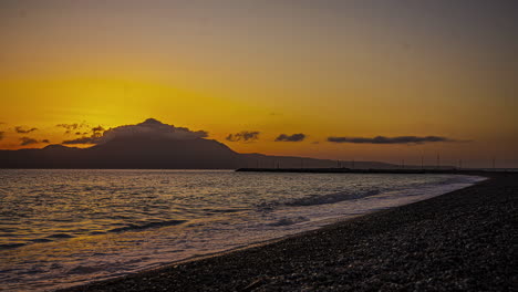 Lapso-De-Tiempo-Fondo-De-Montaña-Puesta-De-Sol,-Playa-De-Arena-Negra,-Olas-Llegando-A-La-Orilla