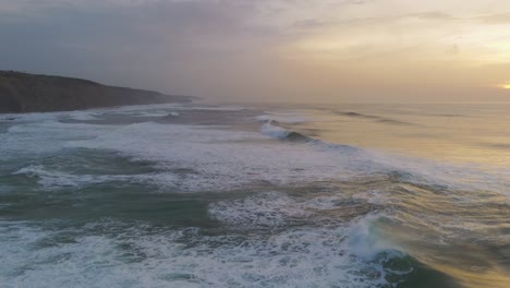 Waves-of-Atlantic-Ocean-crashing-at-sunset-in-Magoito-Beach,-Portugal