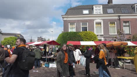 People-enjoying-King's-Day-at-a-bustling-market-in-Utrecht,-Netherlands-under-a-partly-cloudy-sky