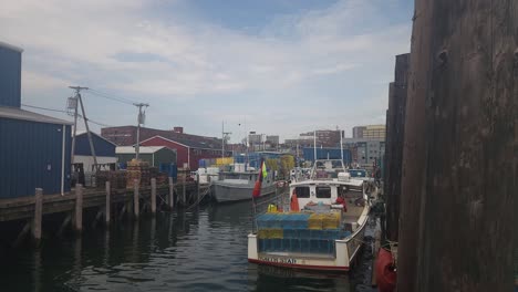 Crowded-working-harbor-in-Portland,-Maine,-showing-boats-at-the-pier,-lobster-traps,-bait-pails,-and-storage-buildings