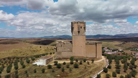 Belalcazar-castle-in-cordoba,-spain-with-surrounding-landscape-under-a-partly-cloudy-sky,-aerial-view