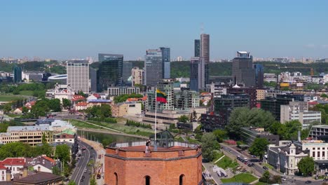 Waving-Lithuanian-Flag-Revealed-Above-Gediminas-Tower-with-Modern-Skyscrapers-in-Background