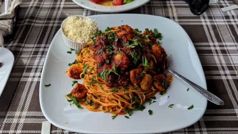 Spaghetti-Bolognese-with-Parmesan-Cheese-on-a-Plaid-Tablecloth,-Zoom-In