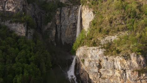 Aerial-view-of-Seerenbach-Falls,-cascading-down-a-rugged-cliff-surrounded-by-lush-greenery,-located-near-Betlis-in-the-Amden-municipality,-Switzerland
