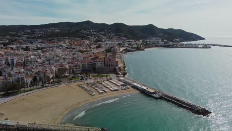 Scenic-aerial-view-of-Sitges-coastline-and-historic-buildings-under-a-sunny-sky