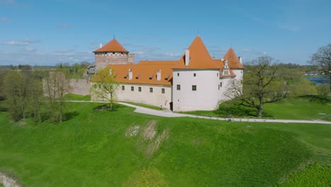 Aerial-establishing-view-of-Bauska-Medieval-Castle-and-ruins,-Musa-and-Memele-rivers-next-to-the-castle,-sunny-spring-day,-ascending-drone-shot-moving-forward