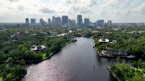 Extracción-Aérea-Del-Horizonte-De-Fort-Lauderdale-Al-Fondo-Con-Casas-De-Lujo-En-Primer-Plano-A-Lo-Largo-Del-Canal