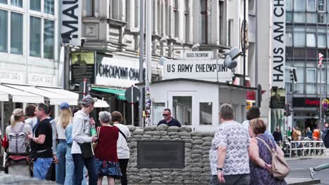 Turistas-Tomando-Fotografías-Detrás-De-Una-Pared-De-Arena-En-El-Checkpoint-Charlie,-Cola-Con-Turistas-Esperando