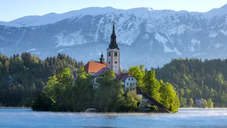 Die-Kirche-Mariä-Himmelfahrt-Auf-Einem-Felsvorsprung-In-Der-Mitte-Des-Bleder-Sees-In-Slowenien,-Umgeben-Vom-Morgendlichen-Nebelschleier