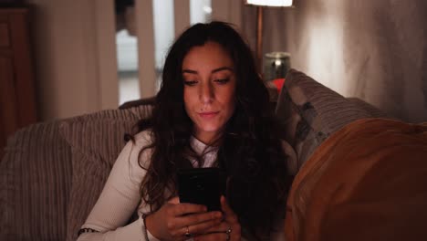 Young-Italian-woman-using-a-smart-phone-while-relaxing-at-home