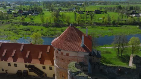 Aerial-establishing-view-of-Bauska-Medieval-Castle-tower-and-ruins,-Musa-and-Memele-rivers-next-to-the-castle,-sunny-spring-day,-orbiting-drone-shot