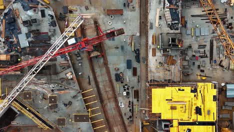 Un-Sitio-De-Construcción-Ocupado-Con-Grúas-Y-Materiales-De-Construcción-Durante-El-Día,-Vista-Aérea