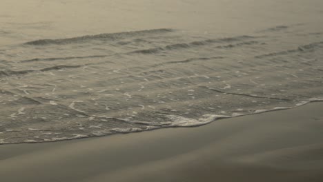 Sanfte-Wellen-Umspülen-Das-Sandufer-Unter-Einem-Sanften-Goldenen-Himmel-Bei-Sonnenuntergang