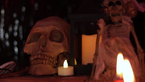 Human-skull,-skeleton-doll-and-burning-candles-in-dark,-Dia-de-Muertos