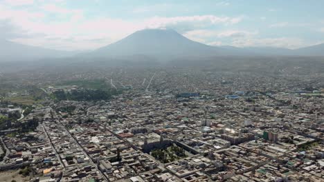 Genießen-Sie-Eine-Atemberaubende-Luftaufnahme-Von-Arequipas-Plaza-De-Armas,-Die-Den-Majestätischen,-Nebligen-Vulkan-Und-Die-Gesamte-Stadt-In-Einem-Spektakulären-Panorama-Zeigt