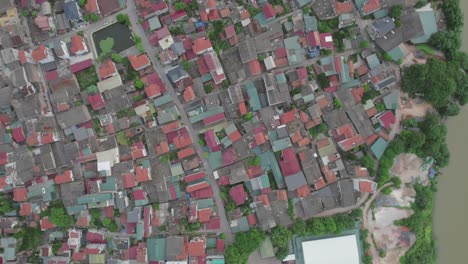Aerial-view-of-densely-packed-residential-neighborhood-by-a-river-in-Hanoi,-Vietnam