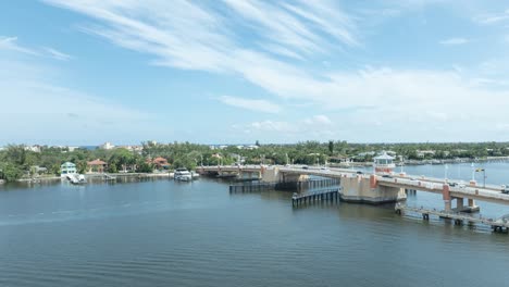 Drohnen-Hyperlapse-Der-Zugbrücke-über-Dem-Intercoastal-Waterway-In-Lantana,-Florida,-Zeigt-Schnell-Fahrende-Boote-Auf-Dem-Wasser-Und-Schnell-Fahrende-Autos-Auf-Der-Brücke