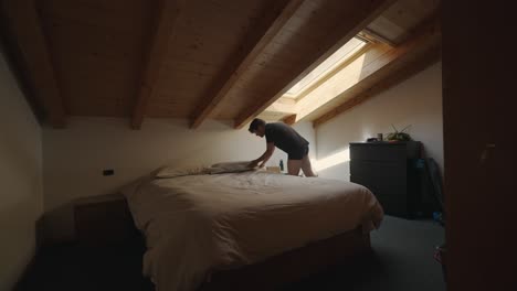 Man-walking-in-the-bedroom-and-getting-into-the-bad-with-sunlight-coming-from-the-roof-window