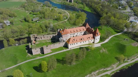Aerial-establishing-view-of-Bauska-Medieval-Castle-and-ruins,-Musa-and-Memele-rivers-next-to-the-castle,-sunny-spring-day,-orbiting-drone-shot