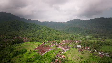 Aerial-Dolly-Errichtet-Häuser-Mit-Roten-Dächern-Am-Fuße-Des-Abhangs-Eines-Tropischen-Berges-Auf-Bali