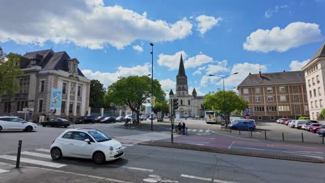 Car-traffic-in-Angers-town-center-with-Eglise-Saint-Laud-church-in-background,-France