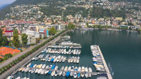 Drone-of-Locarno-Marina,-Luxury-Boats-docked-at-lake-showing-charm-of-this-beautiful-lakeside-town