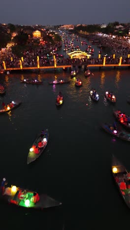 Low-flying-drone-shot-over-lantern-boats-full-of-tourists-for-the-beautiful-Hoi-An-lantern-celebration,-vertical-video