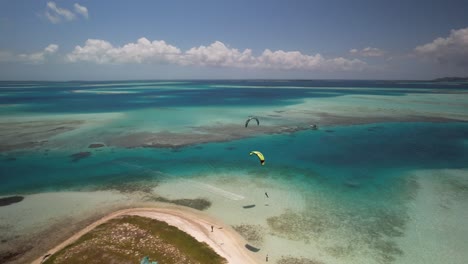 A-kiter-near-sandy-cay-in-turquoise-caribbean-waters,-sunny-day,-aerial-view