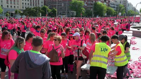 Pink-shirted-participants-hydrate-during-the-Women's-Race,-raising-awareness-about-metastatic-breast-cancer-in-Madrid,-Spain