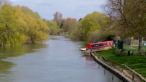 View-of-the-River-Thames-with-red-boat-on-bank-from-floods-in-the-historic-market-town-and-civil-parish-of-Wallingford,-South-Oxfordshire,-England