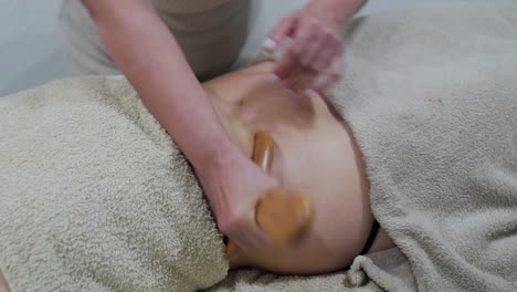 Wood-therapy-massage-on-the-patient's-belly-with-a-shaping-board