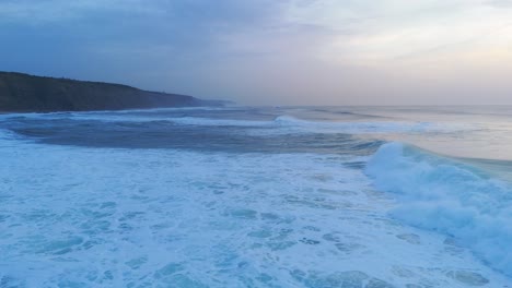 Strong-high-waves-of-Atlantic-Ocean-crashing-at-sunset-in-Magoito-Beach,-Portugal