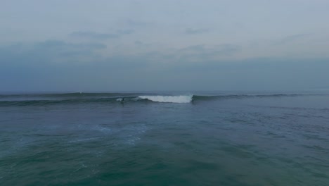 Aerial-shot-of-surfer-surfing-on-wave-between-group-surfer-in-Atlantic-Ocean-during-sunset-time-at-Baleal-Beach,-Portugal