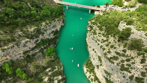 Kayaks-and-boats-float-on-the-turquoise-waters-of-Gorges-du-Verdon-canyon-surrounded-by-steep-cliffs