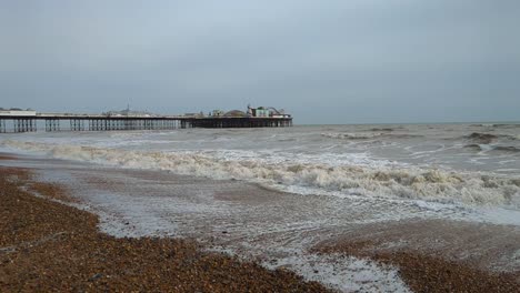 View-of-Brighton-Pier-on-Cloudy-Day-with-Waves-Crashing-in-Slow-Motion