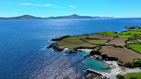 Drone-small-sheltered-fishing-harbour-blue-sea-and-sky-with-mountainous-peninsula-West-Cork-Ireland,Sheep’s-Head-peninsula-on-the-Wild-Atlantic-Way