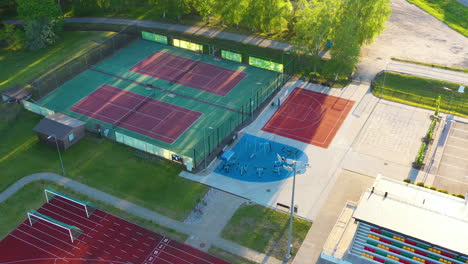 Sports-Complex-with-outdoor-gym-and-tennis-court-in-Smiltene,-Latvia-in-aerial-approaching-view