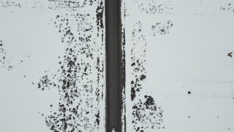 High-above-road-in-winter-with-white-truck-crossing,-aerial-top-down-view