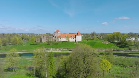 Aerial-establishing-view-of-Bauska-Medieval-Castle-and-ruins,-Musa-and-Memele-rivers-next-to-the-castle,-sunny-spring-day,-wide-drone-shot-moving-forward