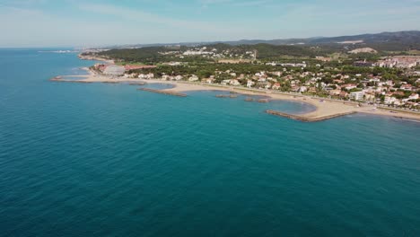 Sitges,-Spanien,-Zeigt-Küste,-Gebäude-Und-Das-Wunderschöne-Blaue-Meer,-Luftaufnahme
