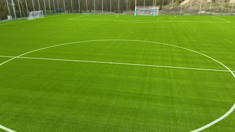 Ein-Gut-Gepflegter-Fußballplatz-Mit-Hellgrünem-Kunstrasen-Und-Weißen-Linien,-Die-Das-Feld-Markieren